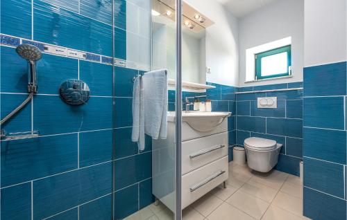 een blauw betegelde badkamer met een wastafel en een toilet bij Lovely Home In Vir With Wifi in Vir