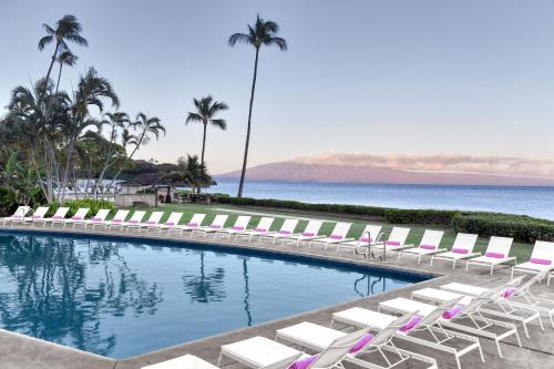 a swimming pool with lounge chairs and the ocean at Kaanapali Ocean Inn in Lahaina