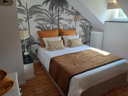 a bedroom with a large bed with palm trees on the wall at Chambre d'hôte des Thermes in Vichy