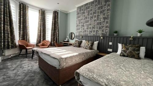a bedroom with two beds and a chair and window at Charlotte Guest House in London