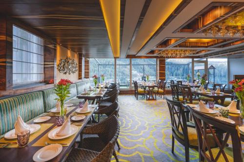 a dining room with tables and chairs and windows at Welcomhotel by ITC Hotels, Shimla in Shimla
