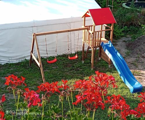 a playground with a slide and red flowers at Willa Epiona in Stepnica