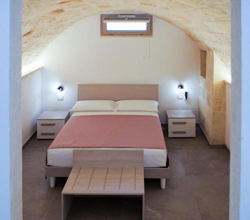 ein Schlafzimmer mit einem Bett, zwei Tischen und einem Fenster in der Unterkunft Perla Suite in Mesagne