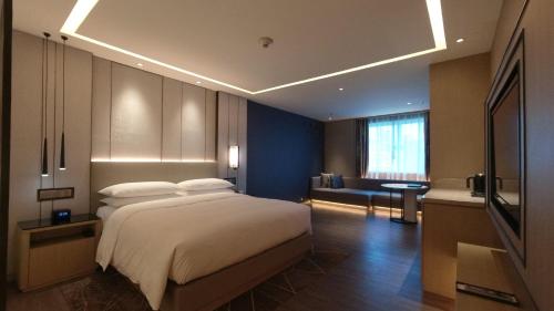 Un dormitorio con una cama grande y una sala de estar. en Renaissance Shenzhen Luohu Hotel, en Shenzhen