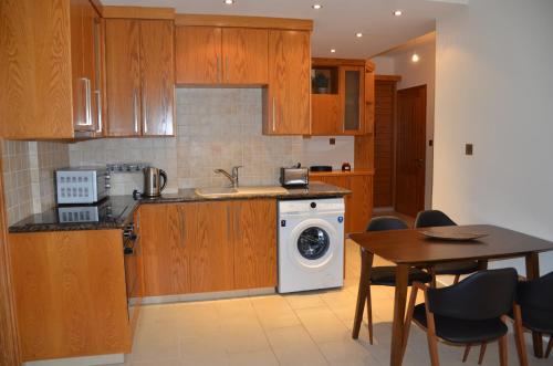 a kitchen with a washing machine and a table at 2 Bedroom Apartment, Zygos Centre Block D - By IMH Travel & Tours in Paphos City