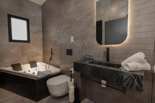 a bathroom with a tub and a toilet and a sink at Alaia Resort- Had Nes אלאיה ריזורט - חד נס in Had Nes