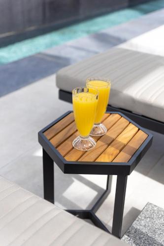 two glasses of orange juice on a table next to a pool at Alaia Resort- Had Nes אלאיה ריזורט - חד נס in Had Nes