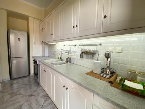 a kitchen with white cabinets and a stainless steel refrigerator at Sunny Apartment Amaliada in Amaliás