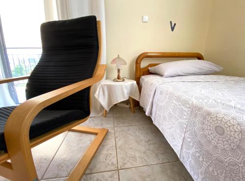 a bedroom with a black chair next to a bed at Sunny Apartment Amaliada in Amaliás