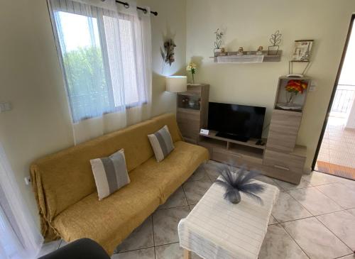 a living room with a couch and a television at Sunny Apartment Amaliada in Amaliás