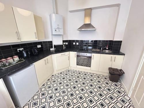 a kitchen with white cabinets and a black and white tile floor at Modern 2 bed apartment in Bristol city centre in Bristol