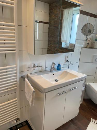 a white bathroom with a sink and a mirror at DreiländerOase in Perl