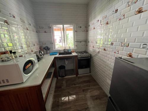 a small kitchen with a stove and a microwave at Chloe's Cottage Self-Catering in La Digue