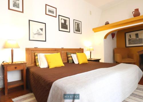 a bedroom with a large bed with yellow pillows at MyStay - Mértola Castelo Palace in Mértola