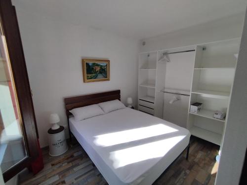 a small bedroom with a white bed and shelves at Sanary Paradise Port Climatisé in Sanary-sur-Mer