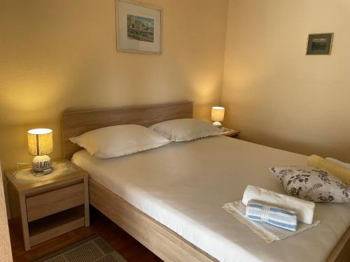 a bedroom with a bed with two pillows and two lamps at Apartments Gordana Buzolic in Hvar