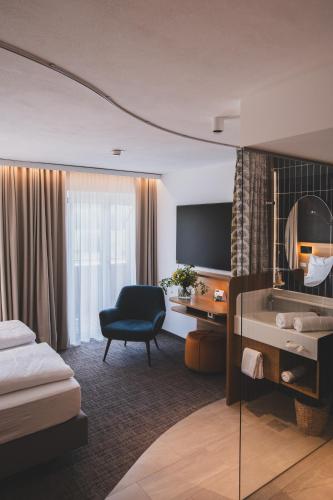 a hotel room with a bed and a desk and a television at TILL Naturhotel - Self-Check-In in Satteins