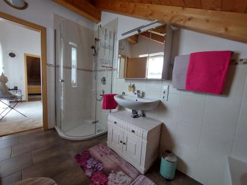 a bathroom with a sink and a shower with pink towels at Ferienwohnung Abendrot in Aßling