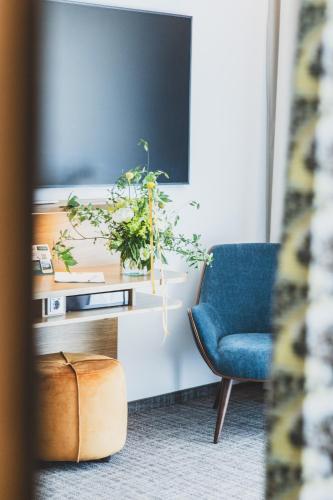 a living room with a blue chair and a tv at TILL Naturhotel - Self-Check-In in Satteins