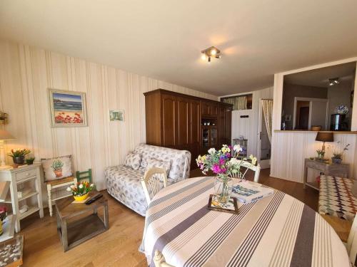 un salon avec une table avec des fleurs dessus dans l'établissement Studio cabine 4 pers avec Parking privé - Saint-Jean-de-Monts - FR-1-224C-103, à Saint-Jean-de-Monts