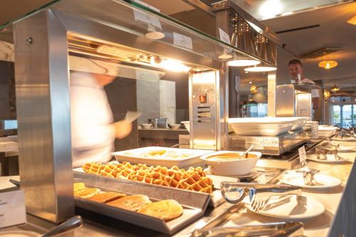 a kitchen with a chef preparing food in a restaurant at Cádiz Bahía by QHotels in Cádiz