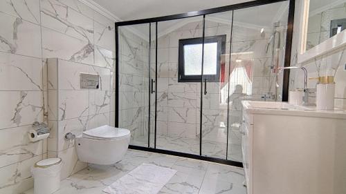 a bathroom with a shower and a toilet and a sink at Göcek Villa Can in Belenpınar