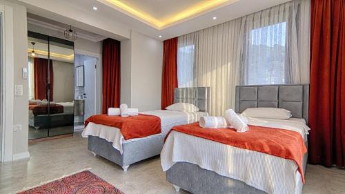 two beds in a hotel room with red curtains at Göcek Villa Can in Belenpınar