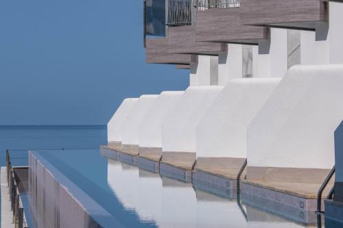 a row of white buildings next to the ocean at Cádiz Bahía by QHotels in Cádiz