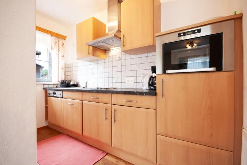 a kitchen with wooden cabinets and a microwave at Almliesl GOLD-705 in Maierhof