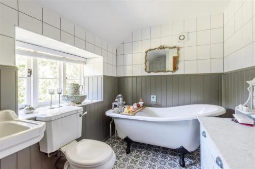 a bathroom with a tub and a toilet and a sink at Berehayes Farmhouse in Bridport