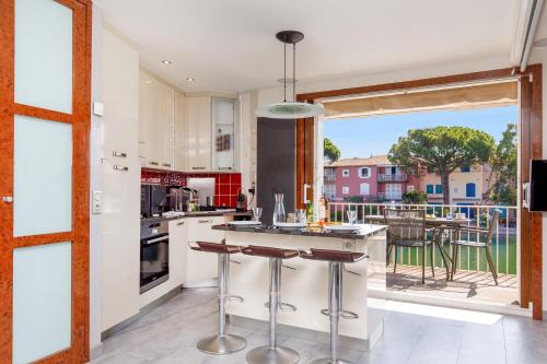 une cuisine avec des placards blancs et une grande fenêtre dans l'établissement Port Grimaud Sud YourHostHelper, à Grimaud