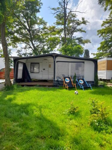 亞斯塔爾尼亞的住宿－Sonata Camp，一辆停放在草地上的大篷车,配有两把椅子