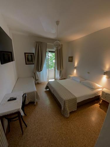 a bedroom with two beds and a table and a window at Hotel Naviglio in Marina di Pietrasanta