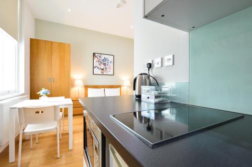 uma cozinha com um balcão preto e uma mesa em Notting Hill Serviced Apartments by Concept Apartments em Londres