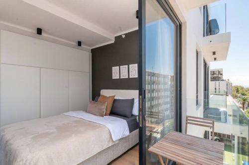 a bedroom with a bed and a glass window at Elegant Green Point Apartment in Cape Town