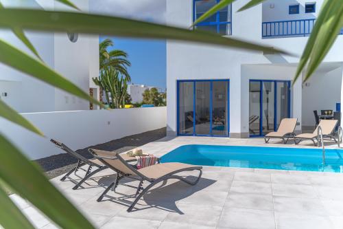 a house with a swimming pool and two lounge chairs at Villas Yaiza in Playa Blanca