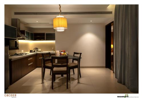 a kitchen with a table and chairs in a room at Cocoon Hotel in Pune