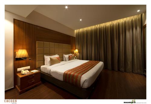 a hotel room with a large bed and a night stand at Cocoon Hotel in Pune