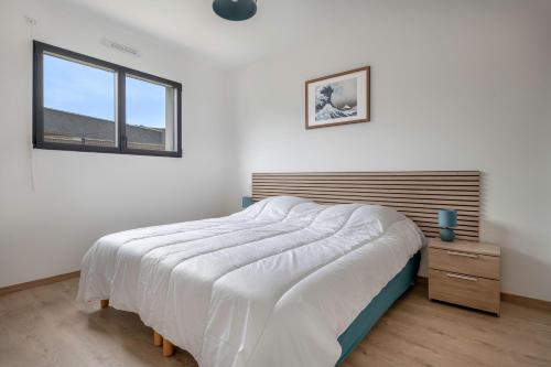 ein weißes Schlafzimmer mit einem großen Bett und einem Fenster in der Unterkunft Instants detente en famille au Tour-du Parc in Le Tour-du-Parc