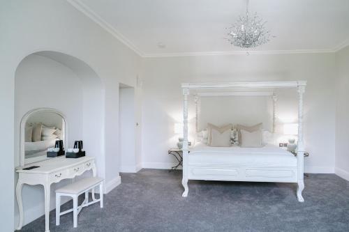 a white bedroom with a white bed and a desk at Highfield Hall in Mold