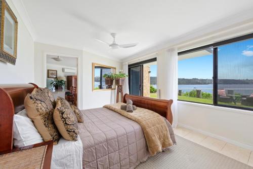 a bedroom with a bed and a large window at Waterfront on Manly Harbour in Sydney