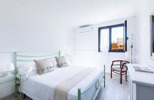 een witte slaapkamer met een bed en een stoel bij Casa Papa in Castelfiorentino