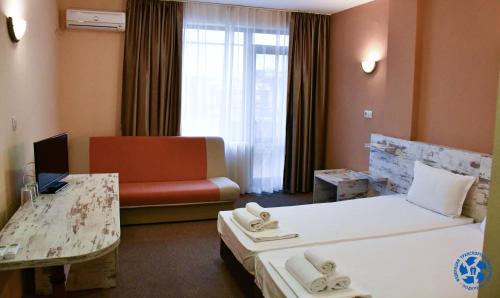 een hotelkamer met 2 bedden en een bank bij Хотел ФТР Подкрепа(Вивас) in Primorsko