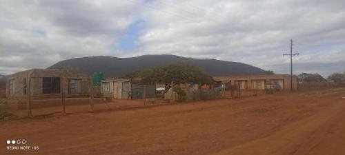 a dirt road with houses and a mountain in the background at Nakedi Accommodation Services in Burgersfort