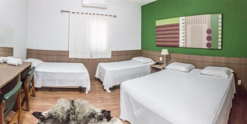 2 camas en una habitación con paredes verdes y sábanas blancas en Samambaia Executive Hotel, en Taubaté