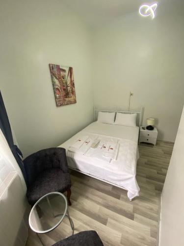ein Schlafzimmer mit einem weißen Bett und einem Stuhl in der Unterkunft Heybeliada Pansiyon in Istanbul