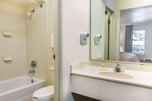 a bathroom with a sink and a toilet and a mirror at Days Inn by Wyndham Lake Park/Valdosta in Lake Park