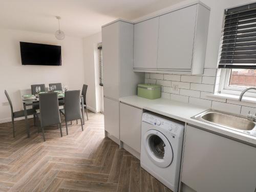 a kitchen with a washing machine and a table with chairs at 39 Mariners Quay in Port Talbot
