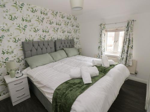 sypialnia z dużym łóżkiem z białą pościelą i tapetą w kwiaty w obiekcie 39 Mariners Quay w mieście Port Talbot