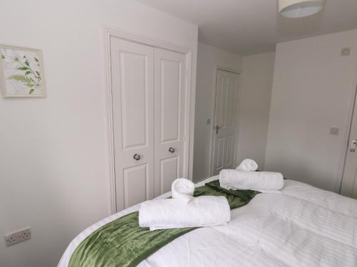 a white bedroom with towels on top of a bed at 39 Mariners Quay in Port Talbot